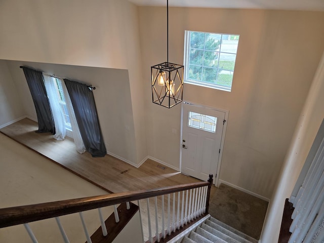 entryway with a chandelier, stairway, baseboards, a high ceiling, and wood finished floors