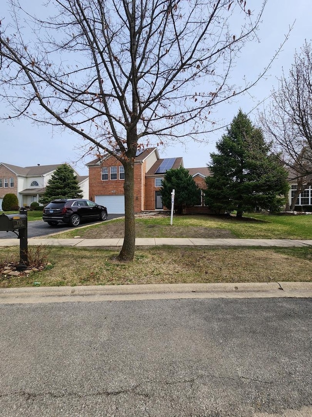 view of front of home featuring brick siding, concrete driveway, solar panels, and a front lawn