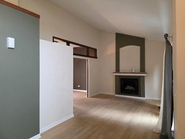 unfurnished living room with light wood finished floors, baseboards, a fireplace, and high vaulted ceiling