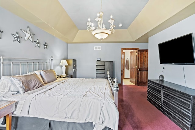 carpeted bedroom with a tray ceiling and a chandelier