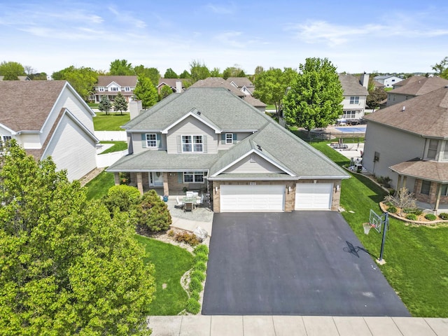 traditional home with driveway, a residential view, a front yard, a garage, and a shingled roof