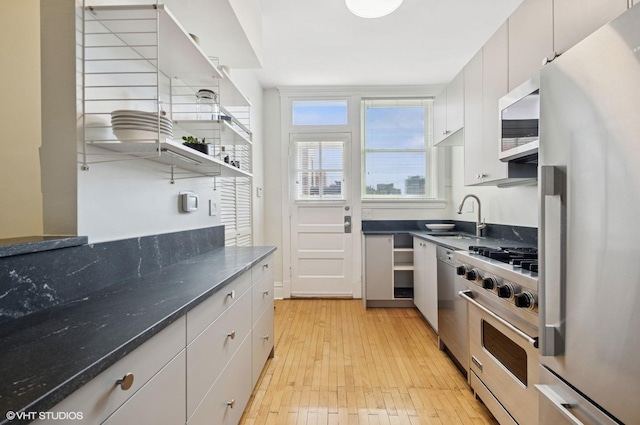 731 W Buckingham Pl Unit 12, Chicago, IL 60657 - kitchen with stainless steel appliances, a sink, light wood-type flooring, white cabinetry, and dark stone countertops
