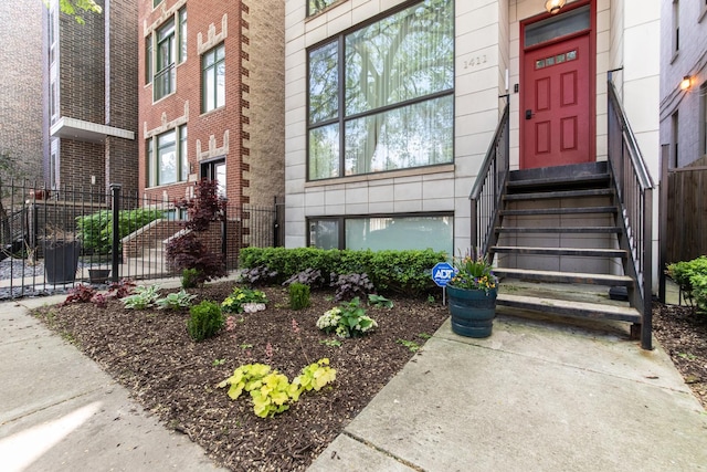 property entrance with fence and brick siding