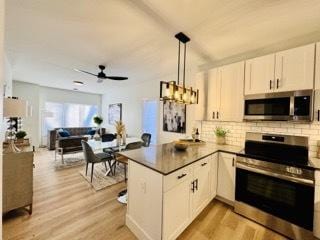 619 N Homan Ave, Chicago, IL 60624 - kitchen featuring stainless steel appliances, a peninsula, light wood finished floors, decorative backsplash, and white cabinets