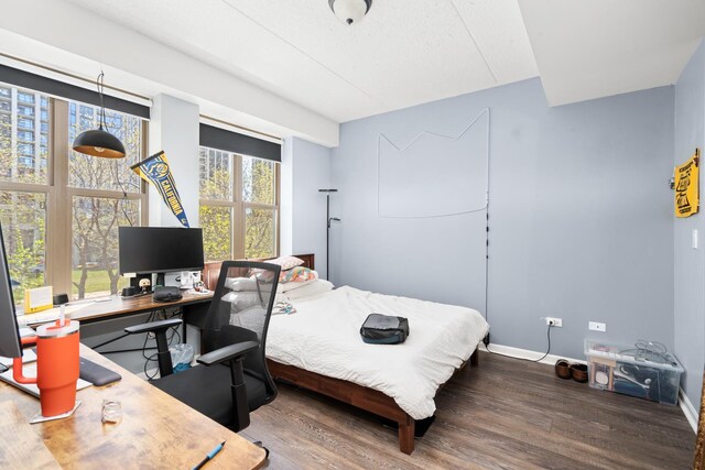 bedroom featuring wood finished floors, an office area, and baseboards