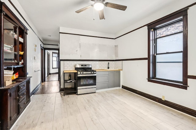 8548 S Manistee Ave, Chicago, IL 60617 - kitchen featuring stainless steel range with gas stovetop, ceiling fan, backsplash, light wood-type flooring, and baseboards