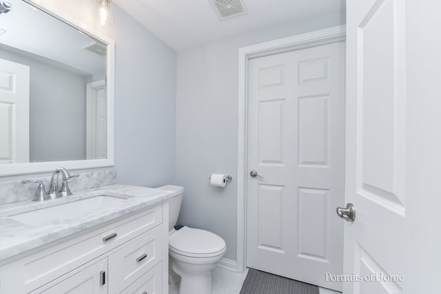 bathroom with toilet, vanity, and tile patterned floors