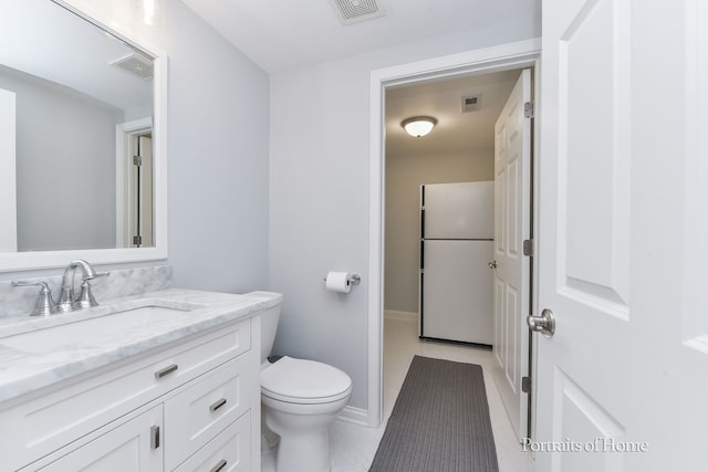 bathroom featuring toilet, vanity, baseboards, and tile patterned flooring
