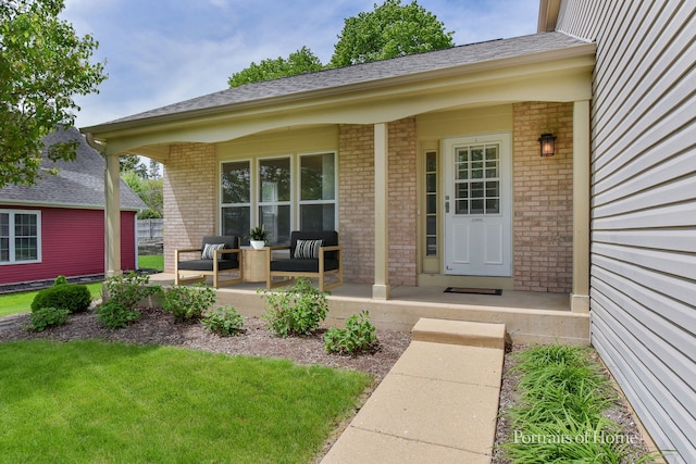 doorway to property with a porch, brick siding, and a lawn