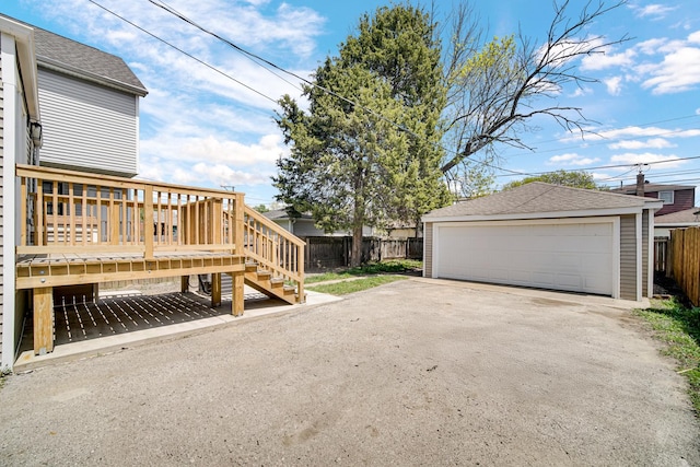 view of yard with fence, stairs, an outbuilding, a detached garage, and a deck