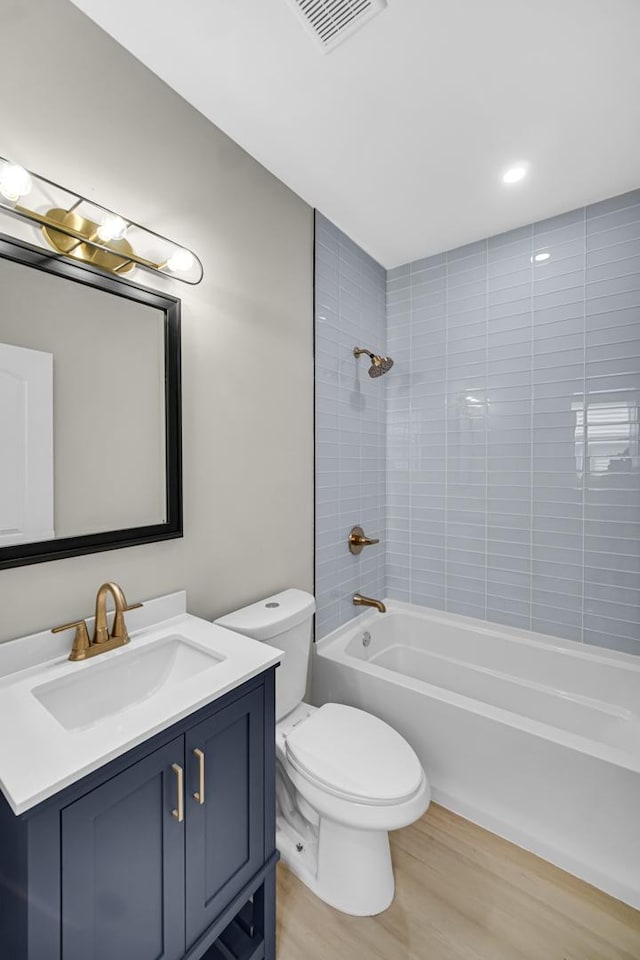 full bath with wood finished floors, vanity, toilet, and bathtub / shower combination