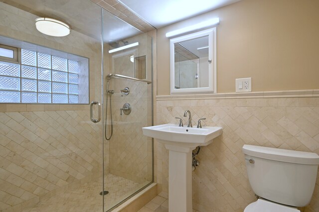 5813 W Eastwood Ave, Chicago, IL 60630 - bathroom featuring a stall shower, toilet, tile walls, a wainscoted wall, and a sink
