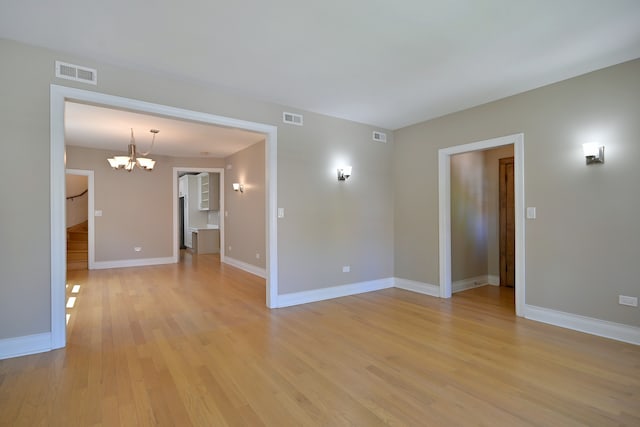 5813 W Eastwood Ave, Chicago, IL 60630 - unfurnished room featuring a chandelier, light wood-style flooring, and baseboards