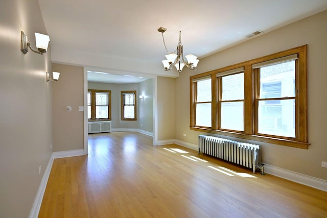 5813 W Eastwood Ave, Chicago, IL 60630 - empty room with radiator heating unit, a chandelier, light wood-type flooring, and baseboards