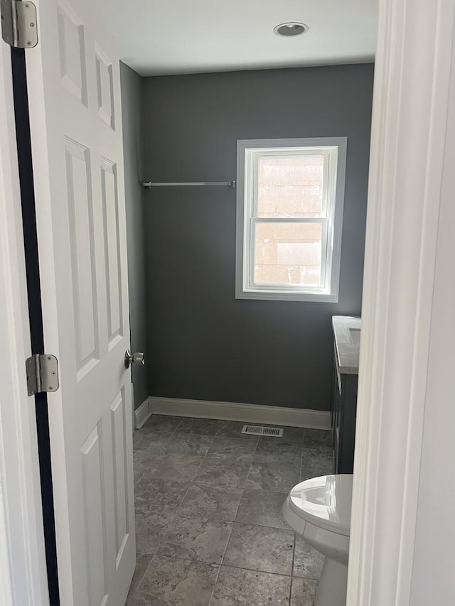 10642 S Calhoun Ave, Chicago, IL 60617 - bathroom featuring toilet, baseboards, vanity, and stone finish flooring