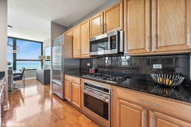 1160 S Michigan Ave Unit 3805, Chicago, IL 60605 - kitchen featuring appliances with stainless steel finishes, decorative backsplash, light wood-type flooring, dark stone counters, and light brown cabinets