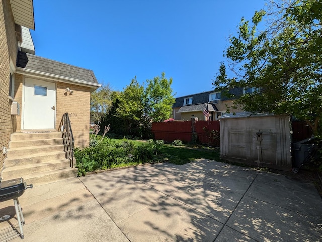 view of patio with entry steps, fence, a storage unit, and an outdoor structure