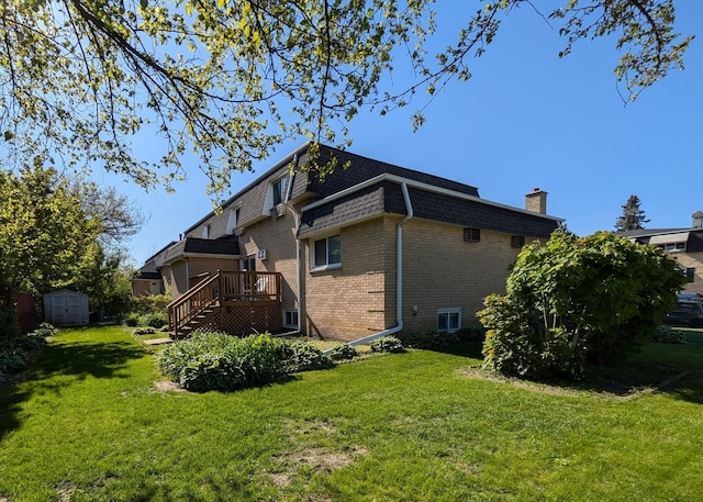 back of property featuring stairway, a shed, brick siding, a lawn, and a deck