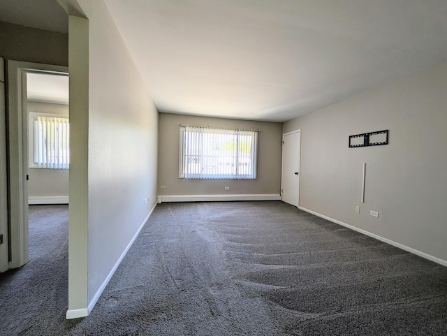 spare room with dark carpet, a baseboard heating unit, and baseboards