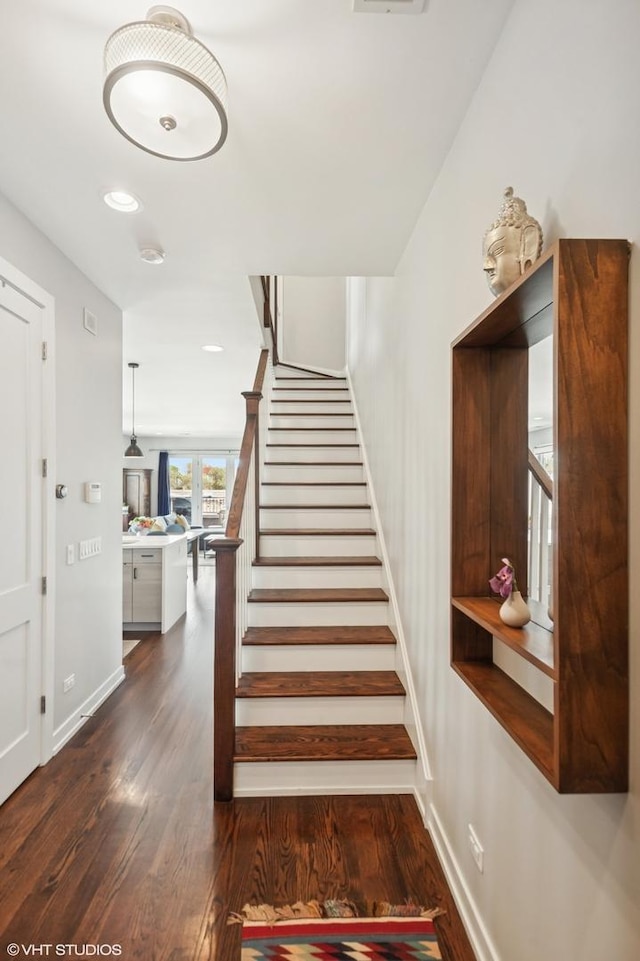 stairway featuring wood finished floors, baseboards, and recessed lighting