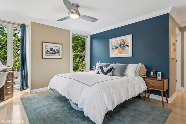 bedroom with light wood-style floors, ornamental molding, multiple windows, and baseboards