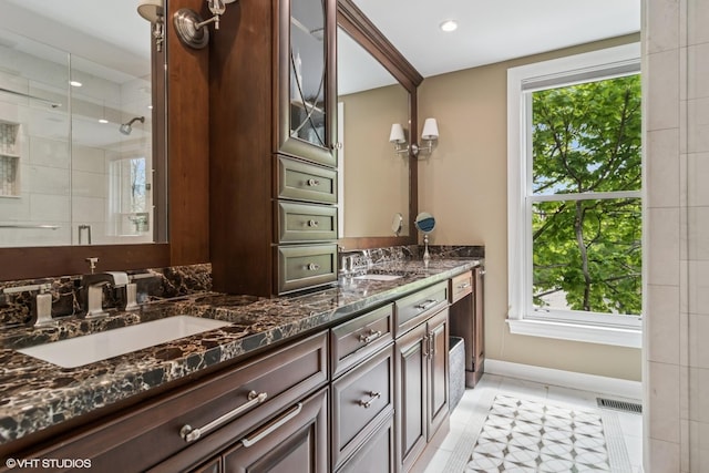 bathroom with a tile shower, double vanity, tile patterned floors, recessed lighting, and baseboards