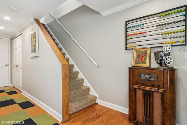 stairway featuring crown molding, baseboards, wood finished floors, and recessed lighting