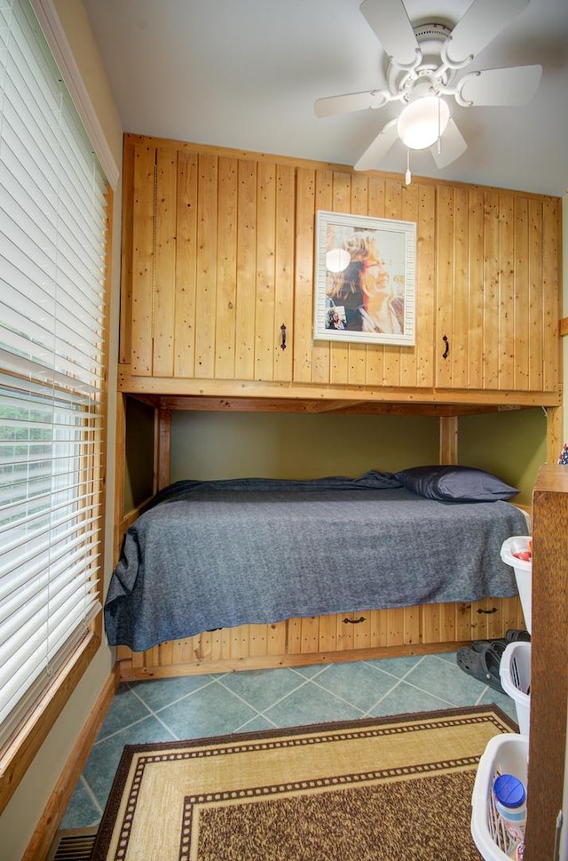 tiled bedroom with wooden walls and ceiling fan