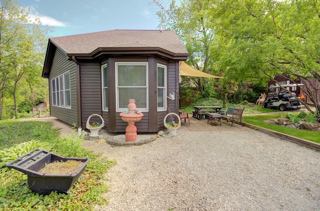 view of property exterior with a patio area and roof with shingles