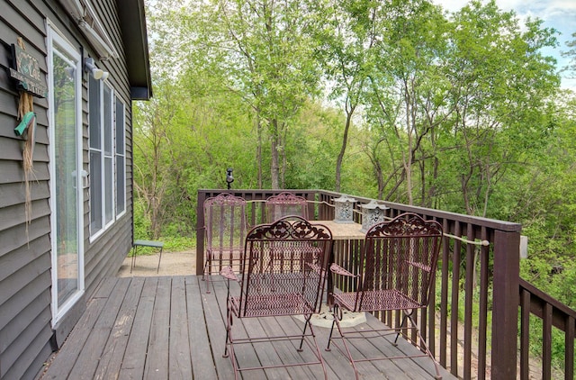 wooden deck featuring outdoor dining area and a view of trees