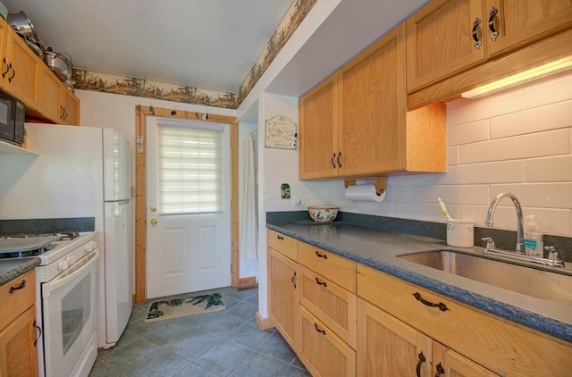 kitchen with white gas stove, a sink, dark countertops, and dark tile patterned flooring