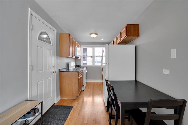 2907 W Summerdale Ave Unit D2, Chicago, IL 60625 - kitchen featuring white appliances, brown cabinetry, light wood-type flooring, baseboards, and dark countertops