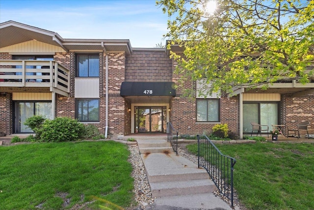 view of front of house featuring a front lawn, brick siding, and french doors