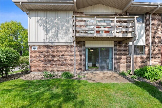 back of property featuring brick siding and a yard