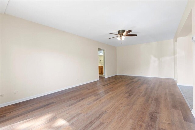 empty room with ceiling fan, wood finished floors, and baseboards
