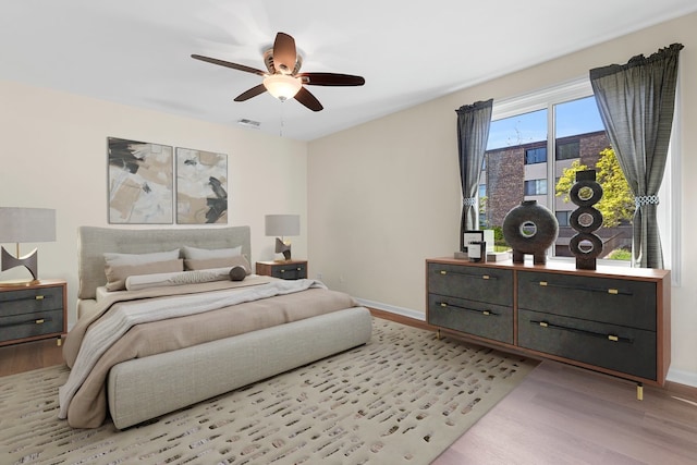bedroom featuring wood finished floors, baseboards, and a ceiling fan