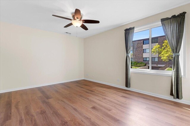 unfurnished room with wood finished floors, ceiling fan, and baseboards