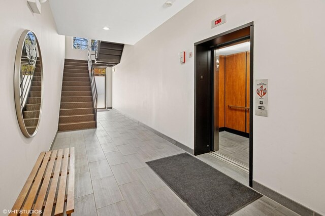 corridor featuring elevator, stairs, recessed lighting, and baseboards