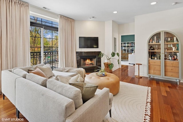 living area with a lit fireplace, wood finished floors, and recessed lighting