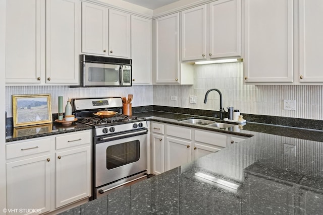 kitchen with appliances with stainless steel finishes, a sink, and dark stone counters