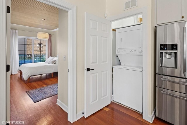 washroom featuring estacked washer and dryer, dark wood-style flooring, and baseboards