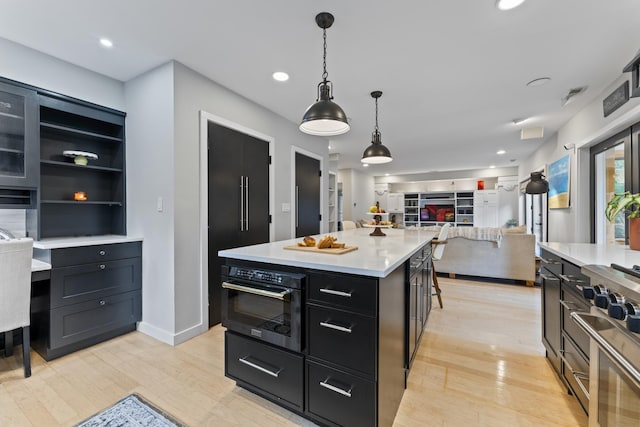 428 S Hillside Ave, Elmhurst, IL 60126 - kitchen featuring oven, dark cabinetry, open floor plan, light wood-style floors, and light countertops