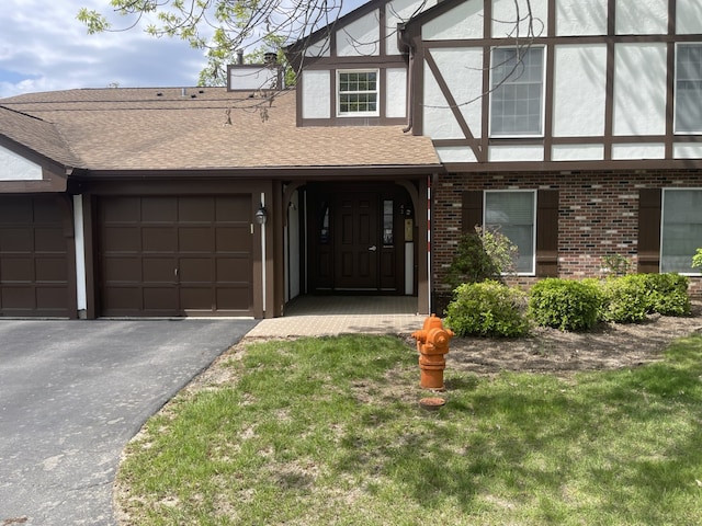 view of front of home featuring an attached garage, asphalt driveway, brick siding, roof with shingles, and stucco siding