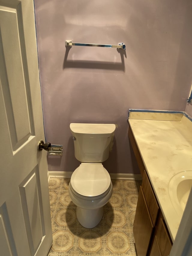 bathroom featuring baseboards, vanity, and toilet