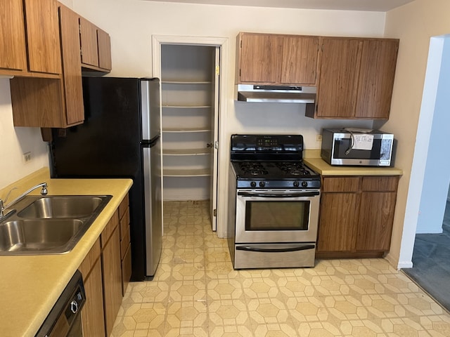 kitchen featuring stainless steel appliances, under cabinet range hood, a sink, light countertops, and light flooring