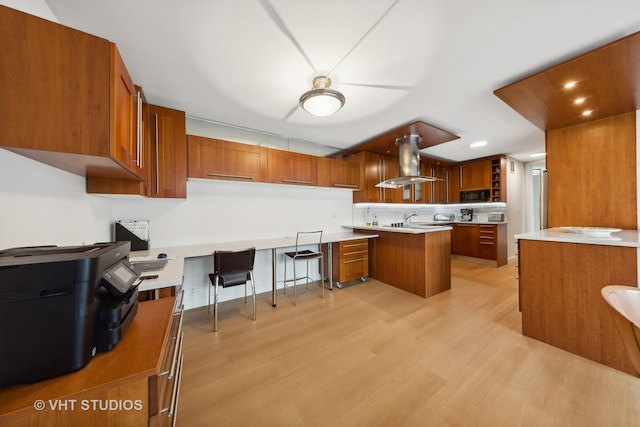 kitchen with island exhaust hood, brown cabinets, black microwave, and recessed lighting