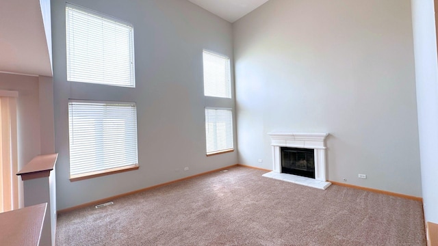6409 Old Plank Blvd, Matteson, IL 60443 - unfurnished living room with carpet flooring, a glass covered fireplace, baseboards, and a high ceiling