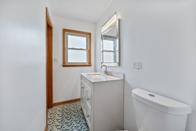half bath with tile patterned floors, toilet, vanity, and baseboards