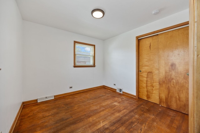unfurnished bedroom with wood finished floors, baseboards, and a closet