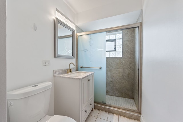 bathroom with a shower stall, toilet, vanity, and tile patterned floors